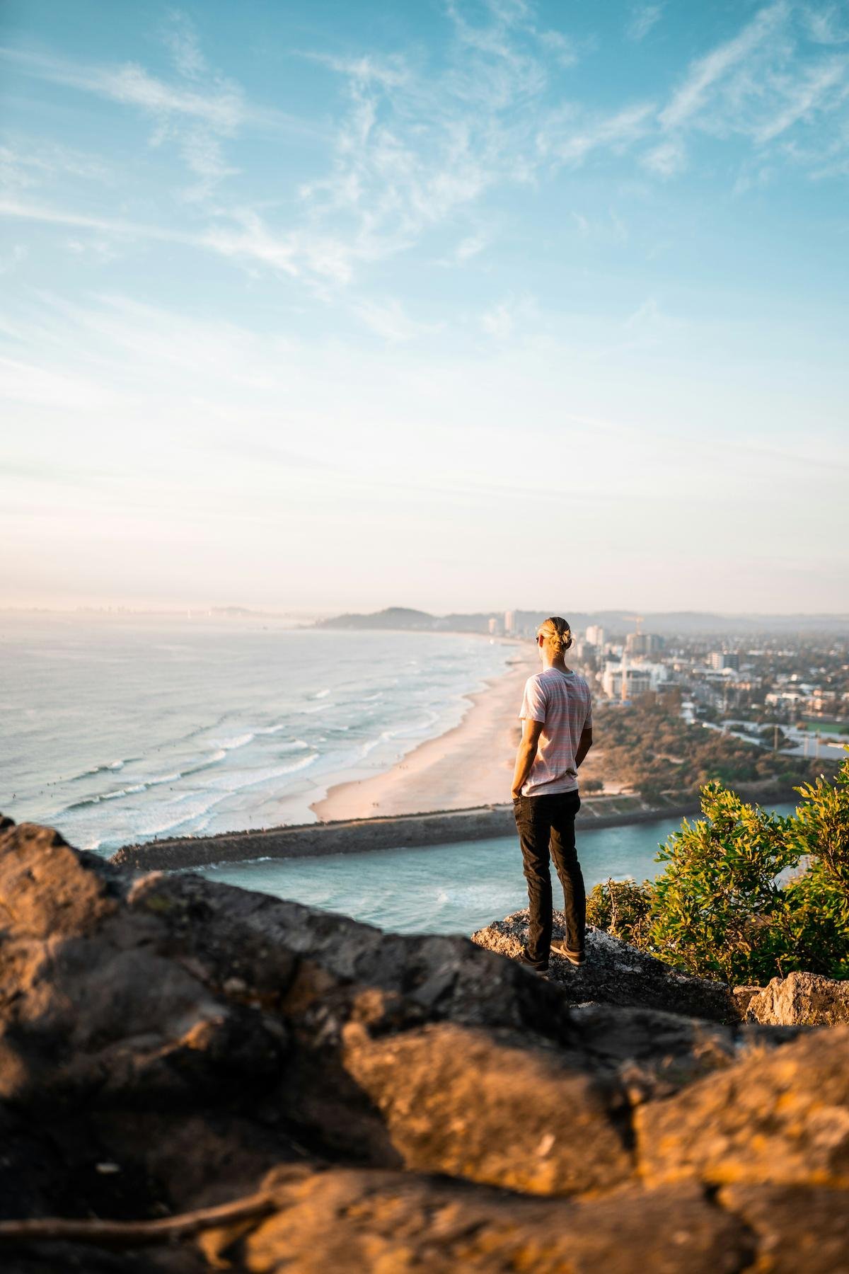 Man standing on rocks looking over Australian beach
