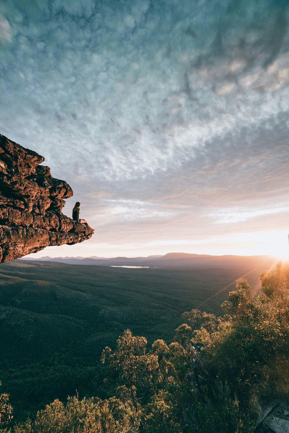 Person on the edge a cliff watching the sun set